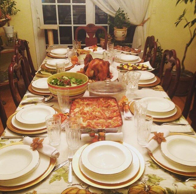 Thanksgiving dinner table with roasted turkey centerpiece and gold-rimmed plates