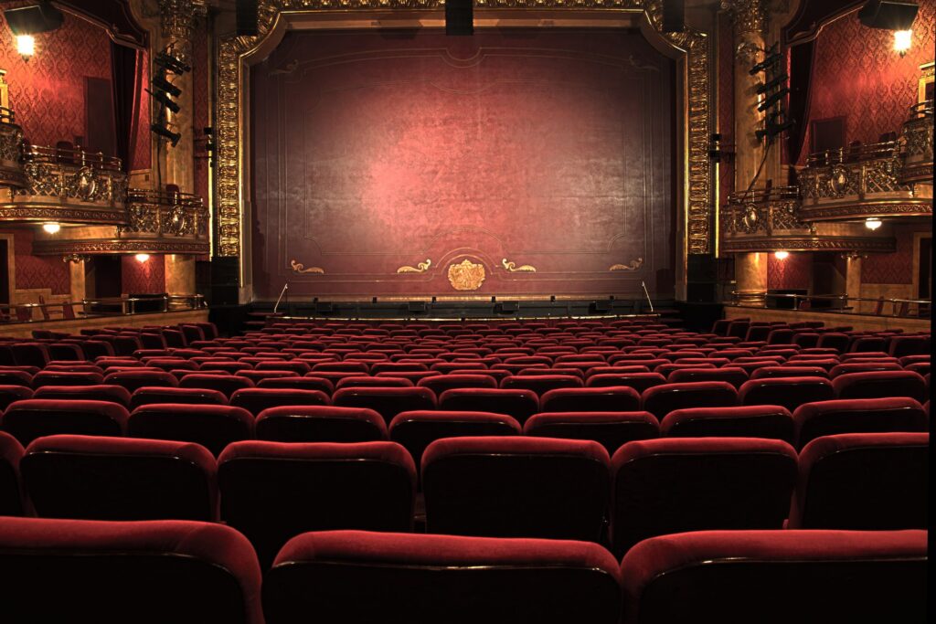 Empty ornate historic theater interior with red velvet seats and burgundy curtain