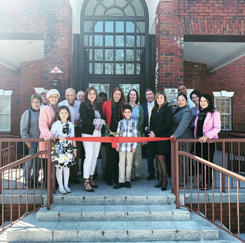 Ribbon-cutting ceremony group photo on red brick building steps
