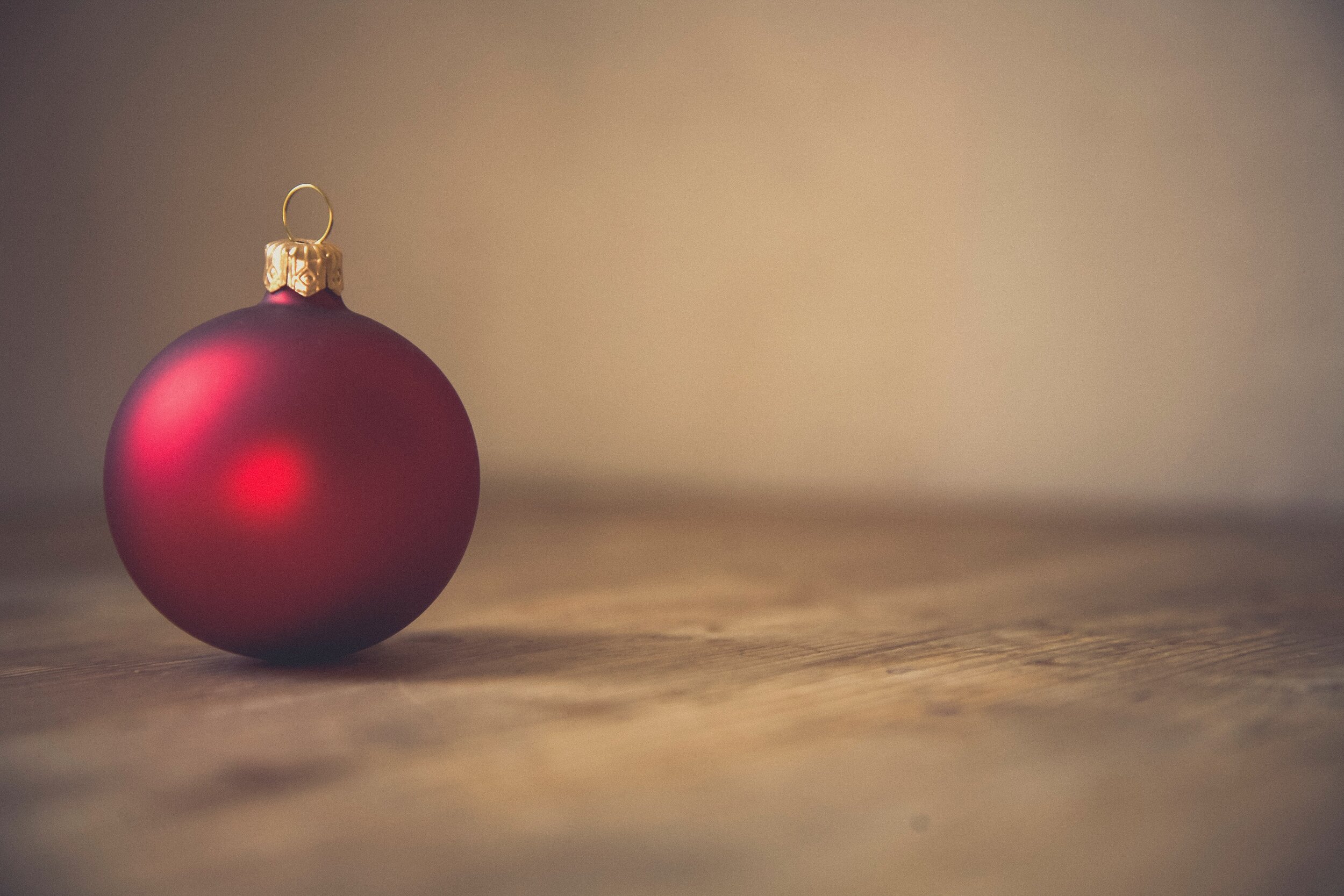 Red Christmas ball ornament with gold cap on wooden surface