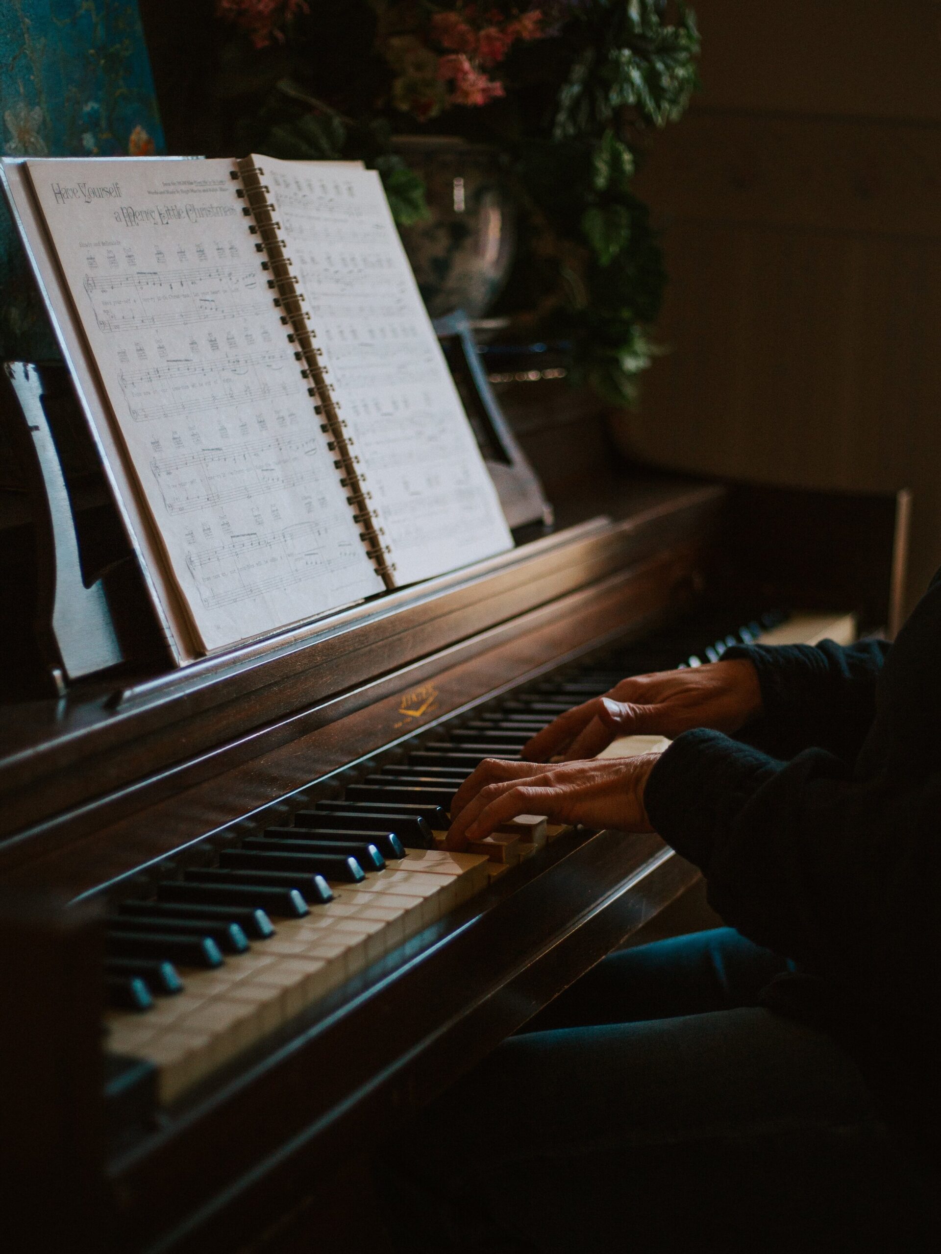 Hands playing wooden piano with Have Yourself a Merry Little Christmas music